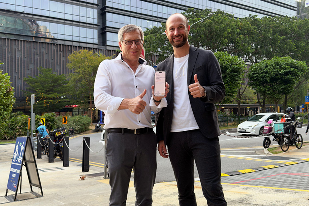 Bernd Schenker und Ulrich Dosch mit der digitalen Gründungsurkunde vor dem zukünftigen Bürogebäude in Singapur Bernd Schenker und Ulrich Dosch mit der digitalen Gründungsurkunde vor dem zukünftigen Bürogebäude in Singapur