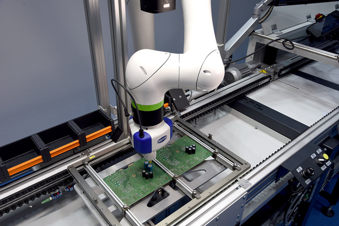 Roboter beim Bestücken einer Platine. Nach erfolgter Umsetzung gibt er sich den Folgeschritt selbst über einen Freigabeschalter frei Roboter beim Bestücken einer Platine. Nach erfolgter Umsetzung gibt er sich den Folgeschritt selbst über einen Freigabeschalter frei